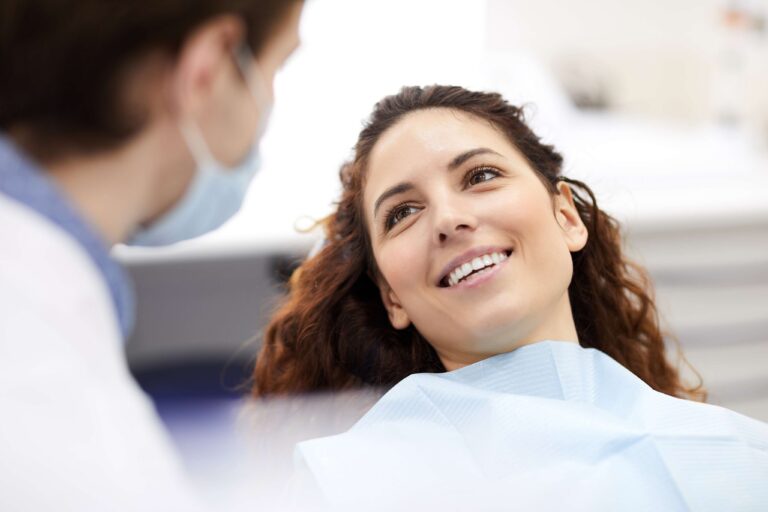 Smiling patient sitting in a dental chair during a consultation with a dentist.